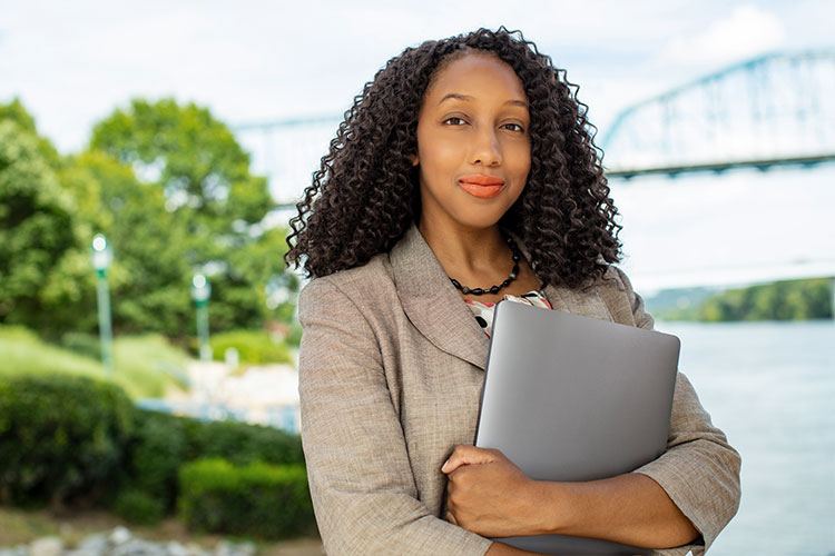 Student April Shaw holding laptop outside