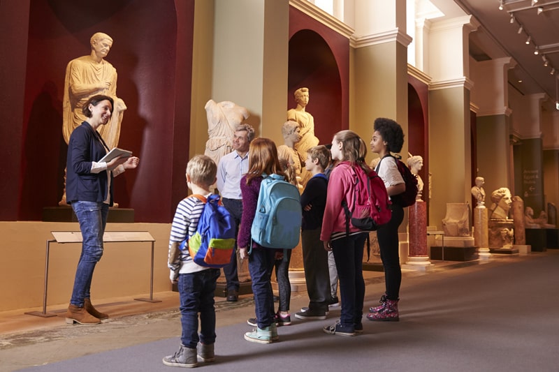 guide walking young students through museum