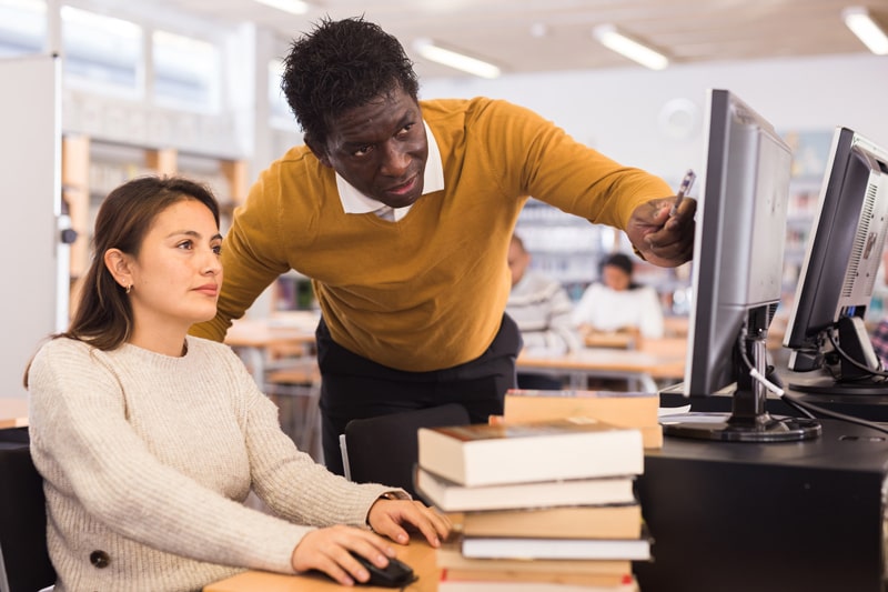 man and woman at computer in library