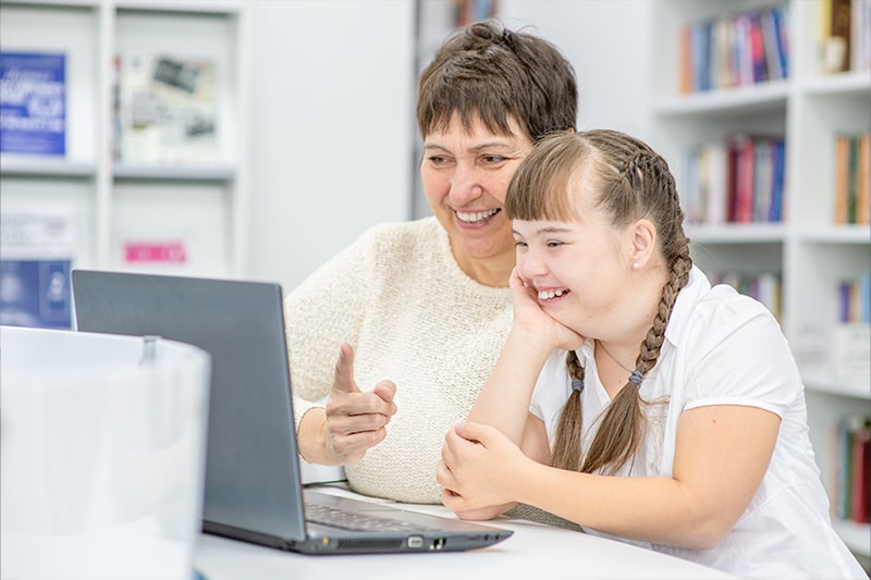 Teacher works with student on her computer.