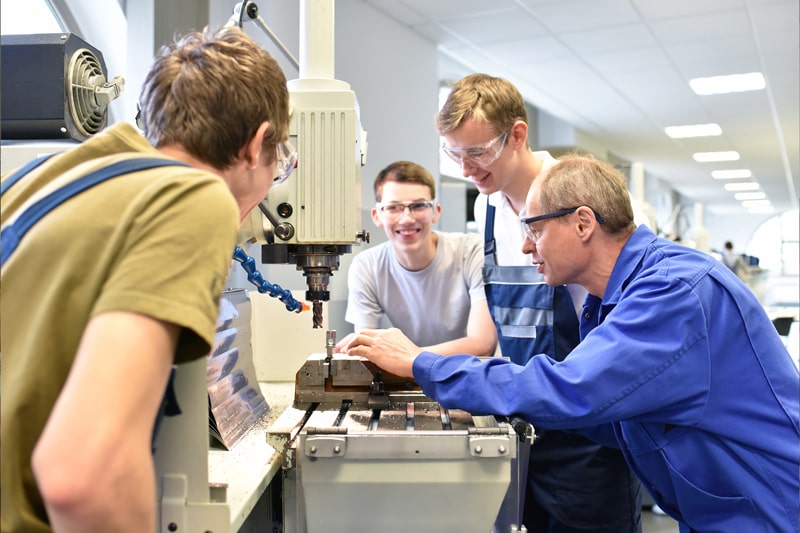 Instructor works with students on using machine for building components.