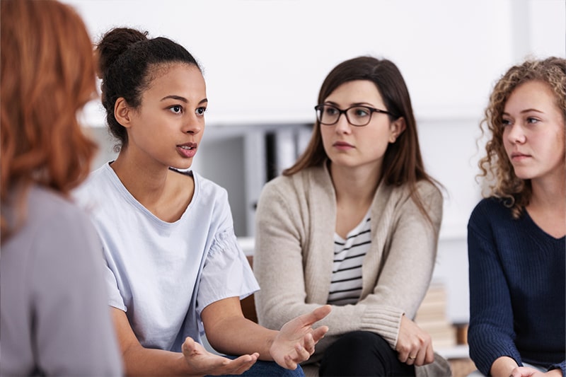 Women sitting in a group discussion setting.