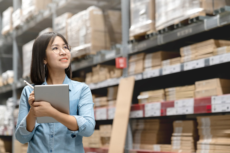 asian woman taking inventory in warehouse