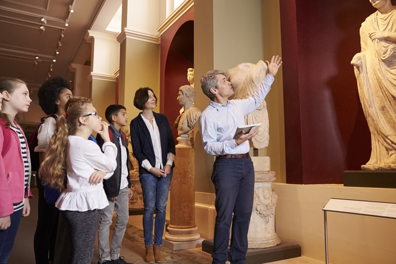 historian explaining statute in museum to visitors
