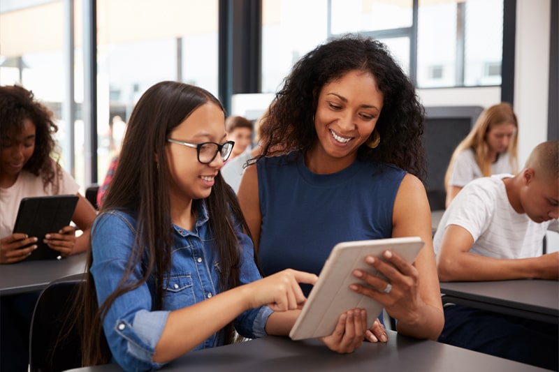 Educator looking at iPad with young student.